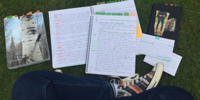 An aerial view photo of Abbie sat crossed-legged on the grass surrounded by study materials.